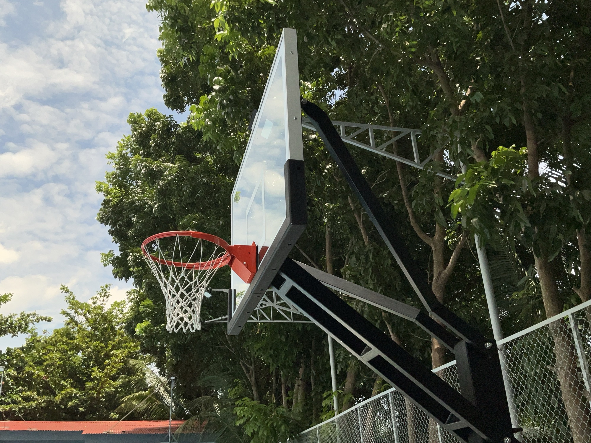 Basketball ring and backboard against a bright sky