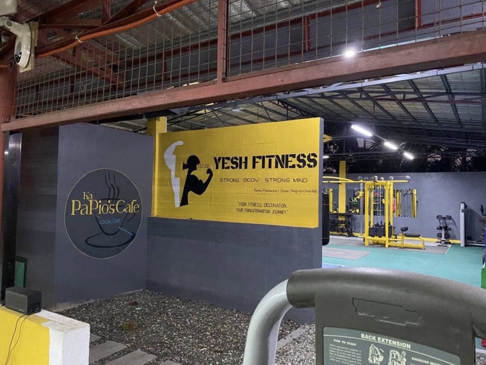 The Yesh Fitness banner and Ka PaPio's Cafe sign painted on the wall inside the gym