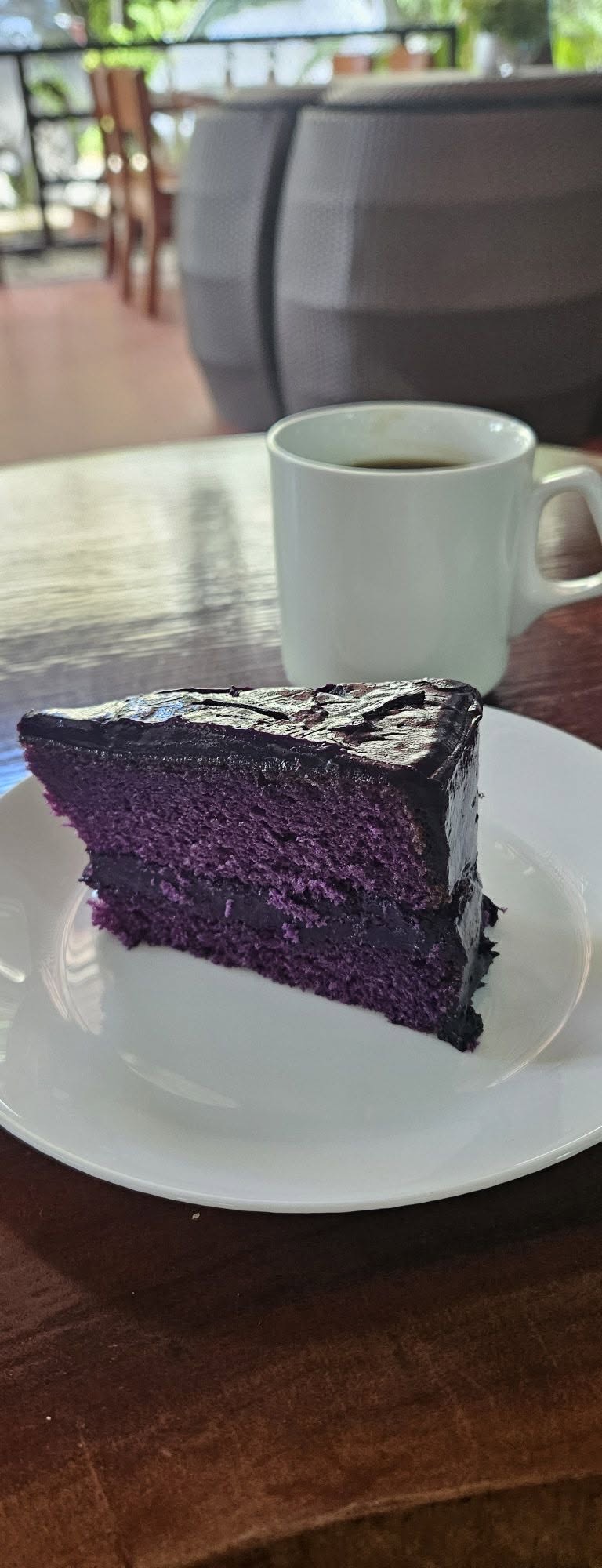 Slice of dark ube cake on a white plate