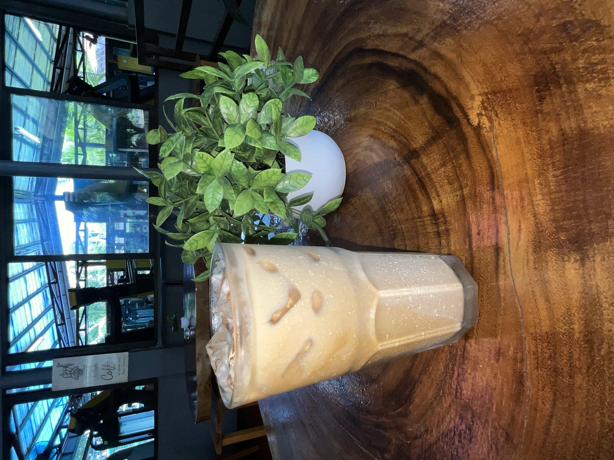 Iced coffee in a tall cup on a live-edge table