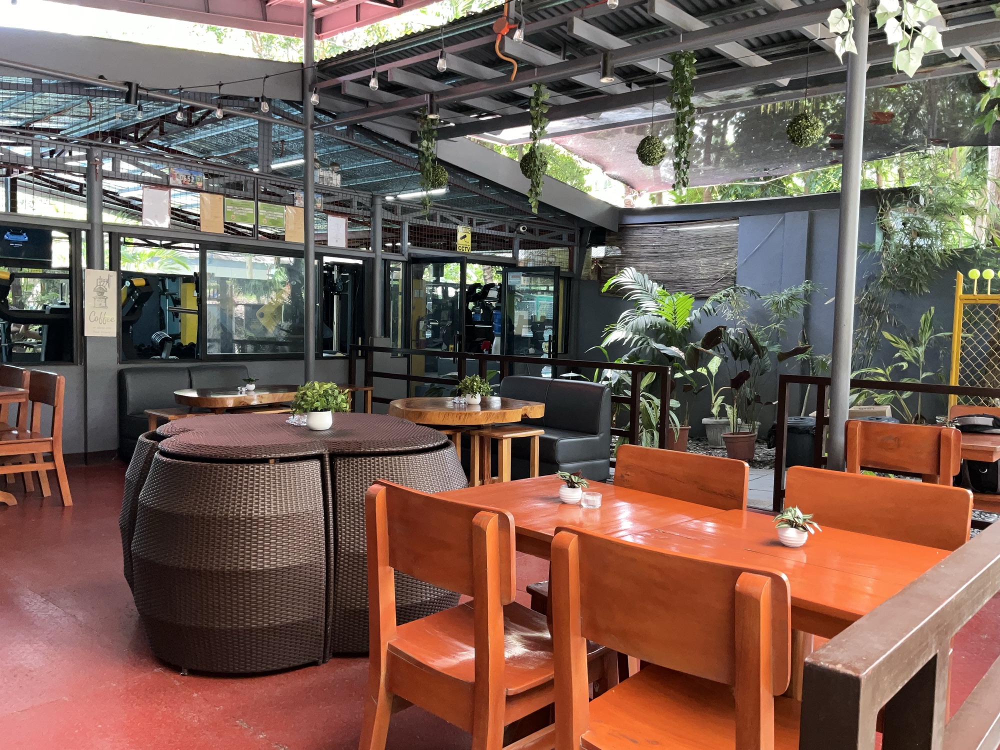 Open-air seating at Ka PaPio's Cafe with wooden tables, orange chairs and plants