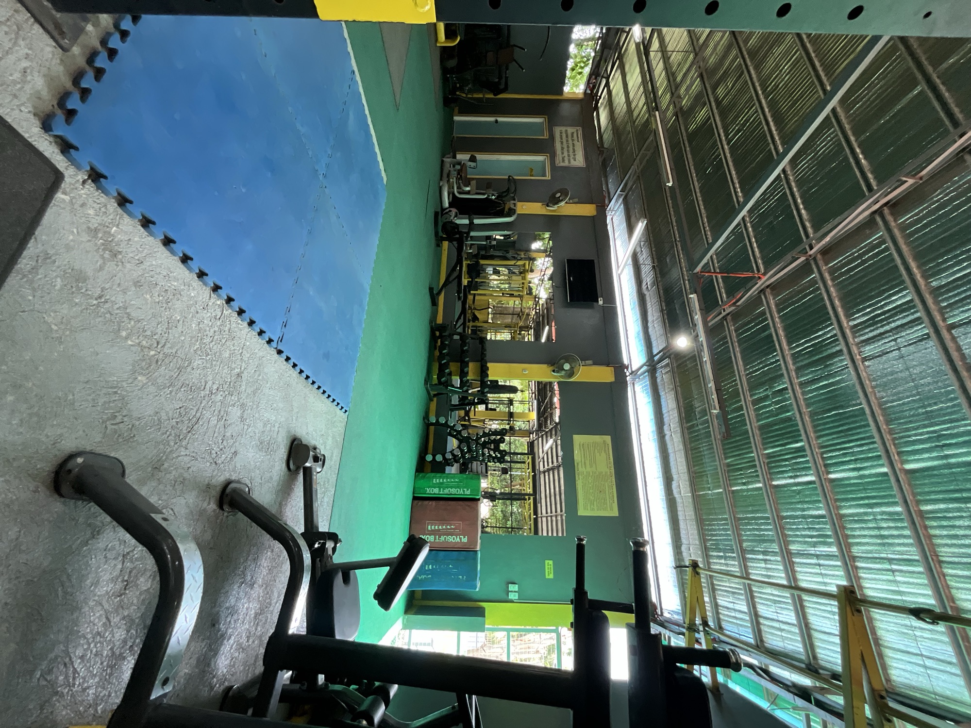 Open-air weight floor with racks, benches and dumbbells at Yesh Fitness