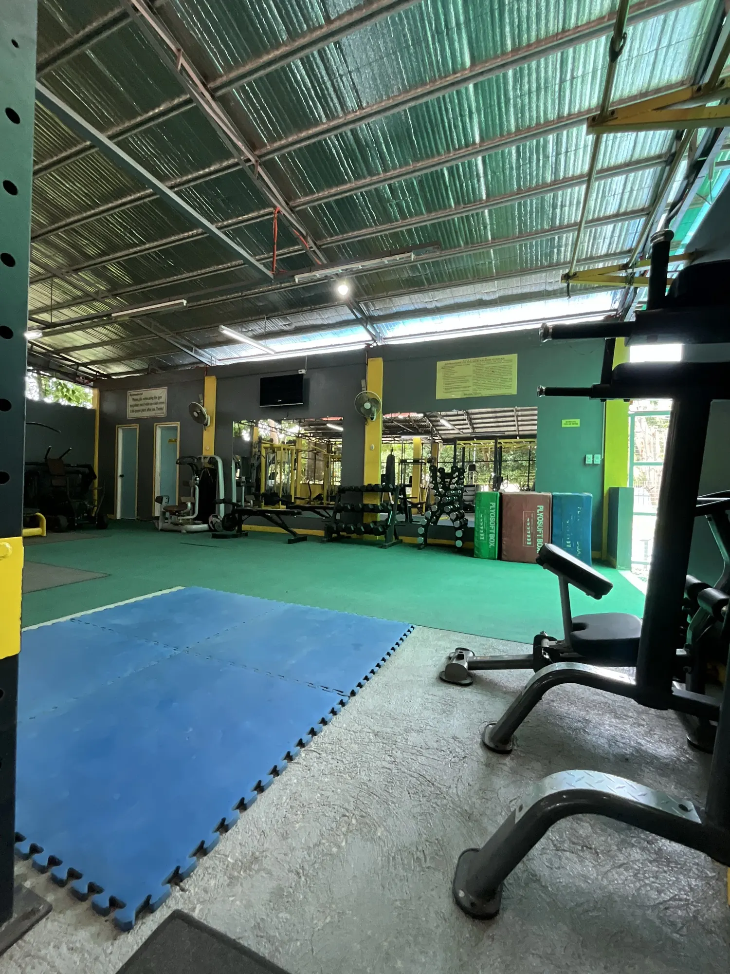 Open-air weight floor with racks, benches and dumbbells at Yesh Fitness