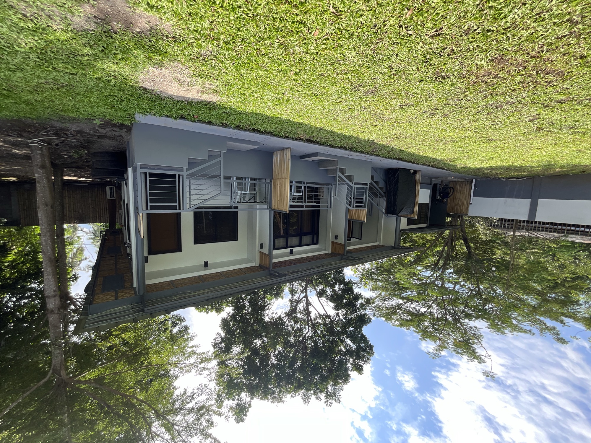 A row of rental rooms with porches facing a green lawn