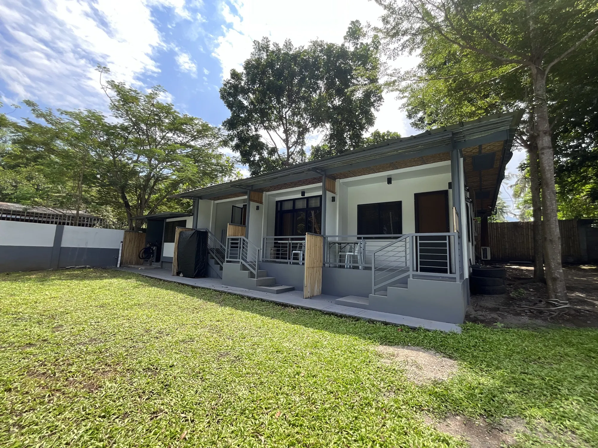 A row of rental rooms with porches facing a green lawn