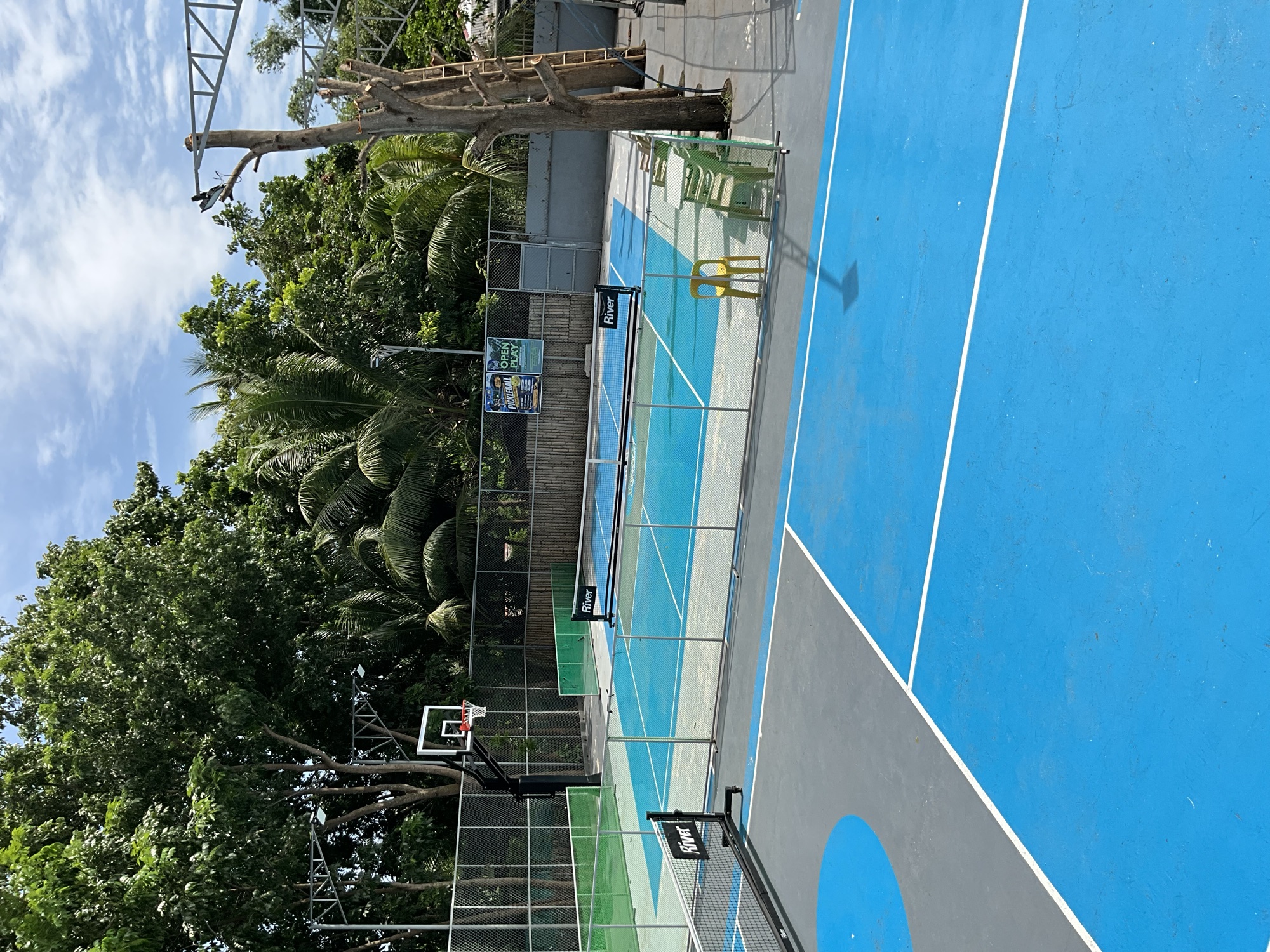 The outdoor pickleball court at Yesh Fitness, freshly painted blue under a bright sky