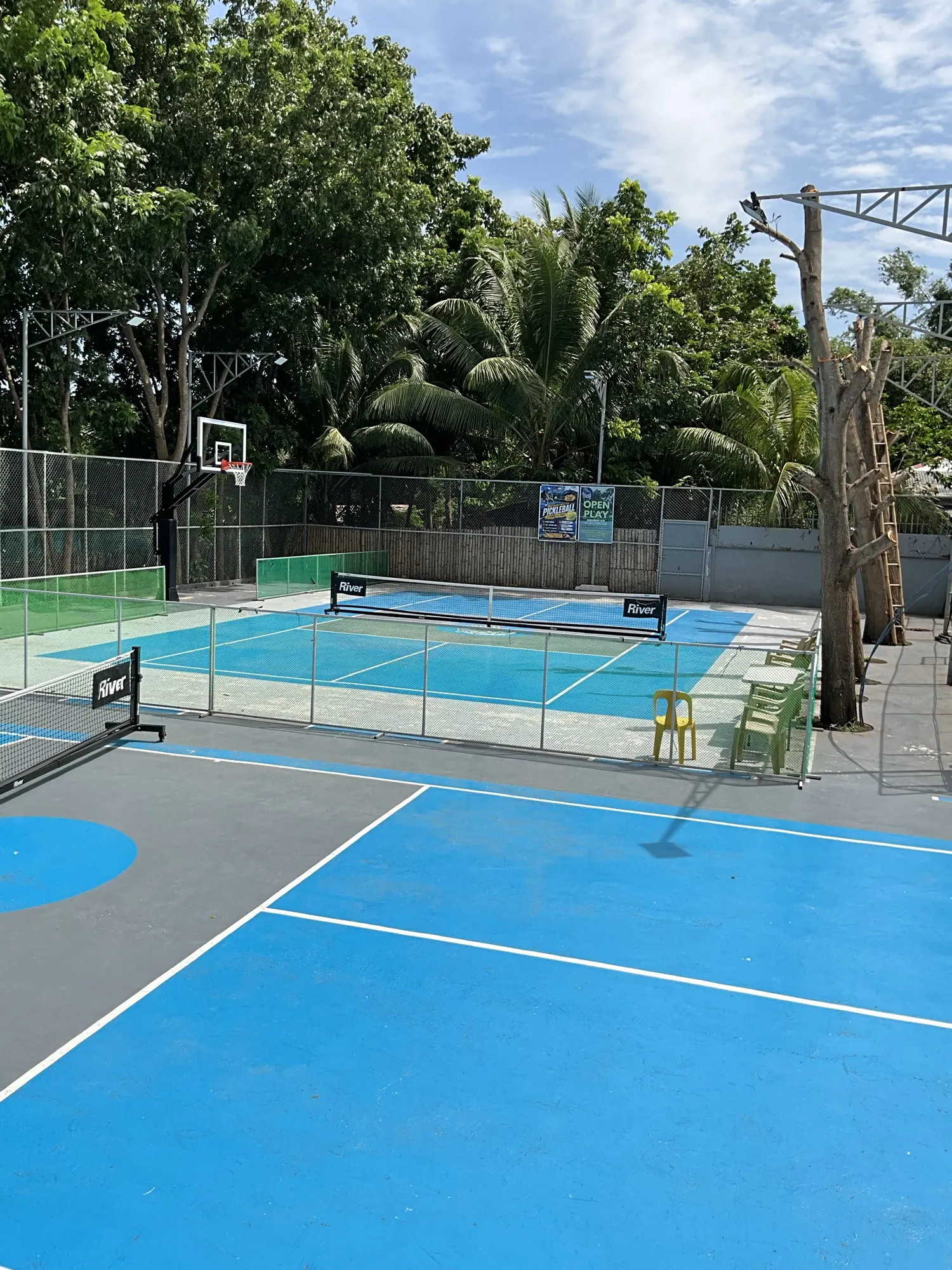 The outdoor pickleball court at Yesh Fitness, freshly painted blue under a bright sky