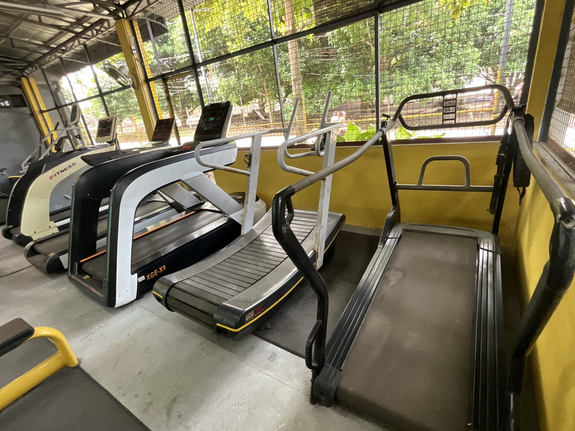 Treadmills and cardio equipment beside the open wall of the gym
