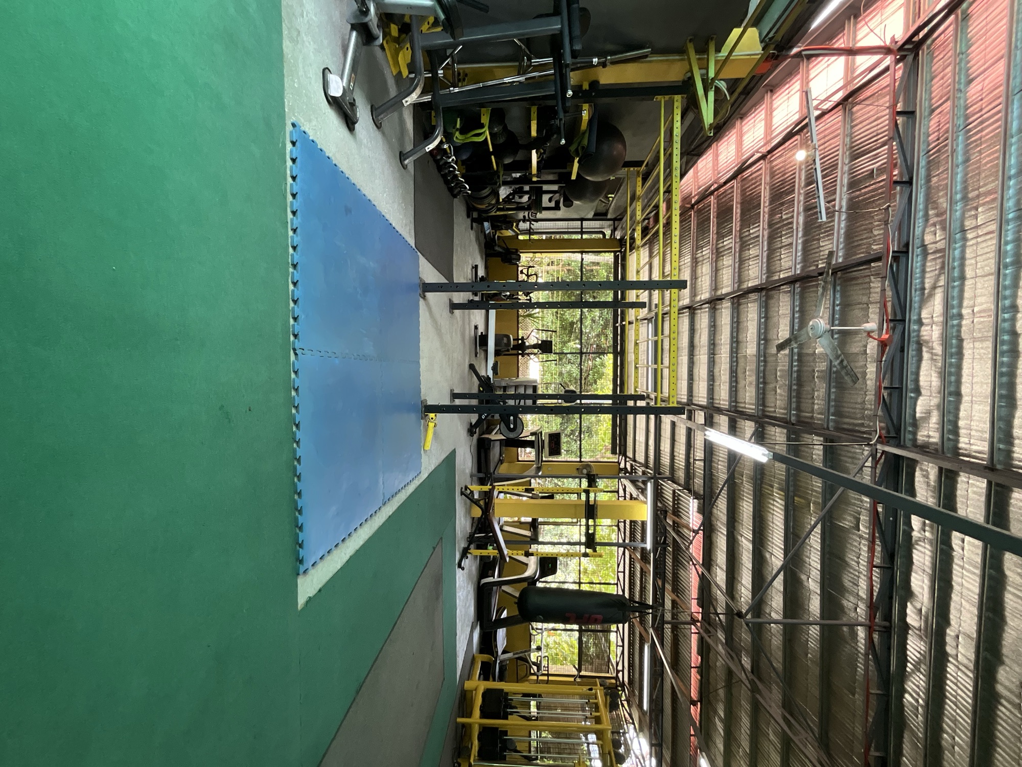 Wide view of the open-air gym floor with mats, rig and heavy bag