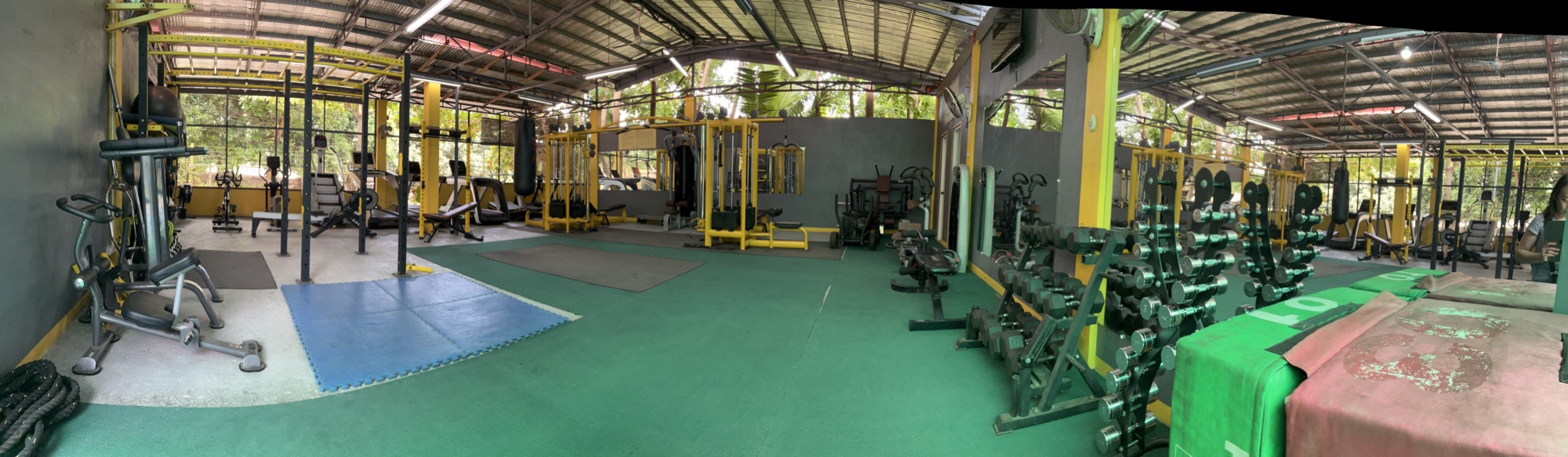 The far end of the gym floor with machines along the green rubber
