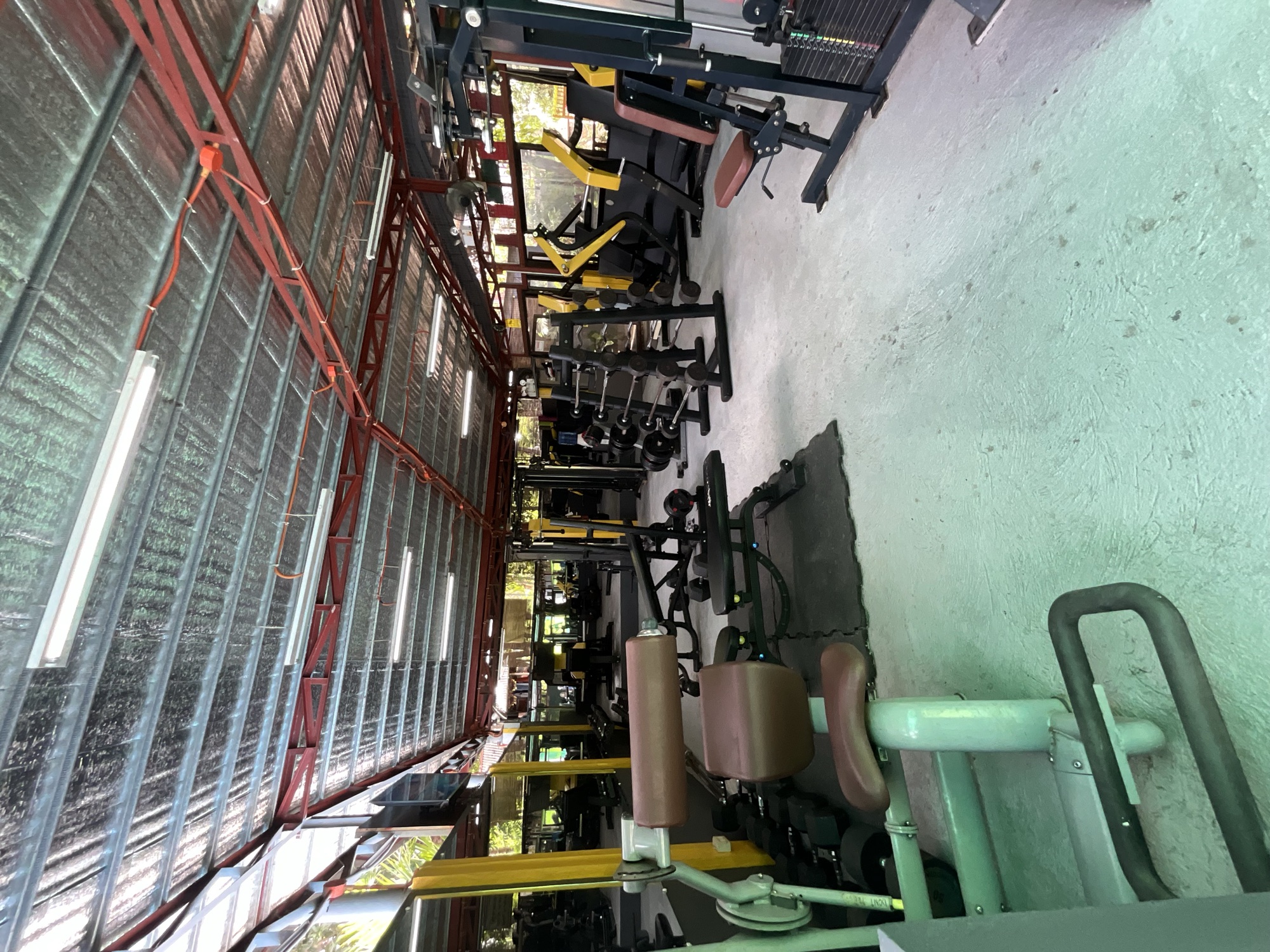 The open-air weight floor at Yesh Fitness Gym in Dauin, machines lined up under a steel roof