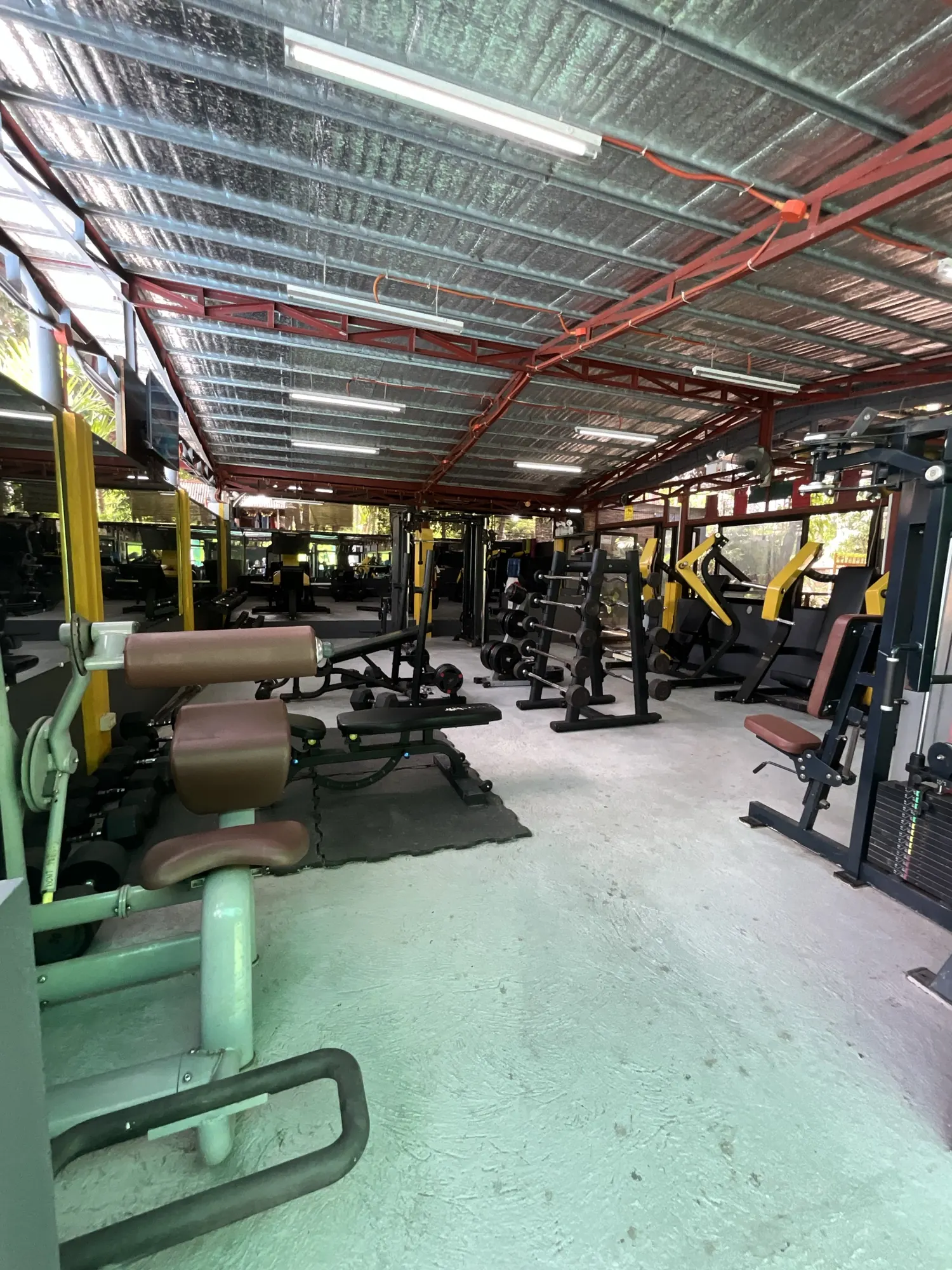 The open-air weight floor at Yesh Fitness Gym in Dauin, machines lined up under a steel roof