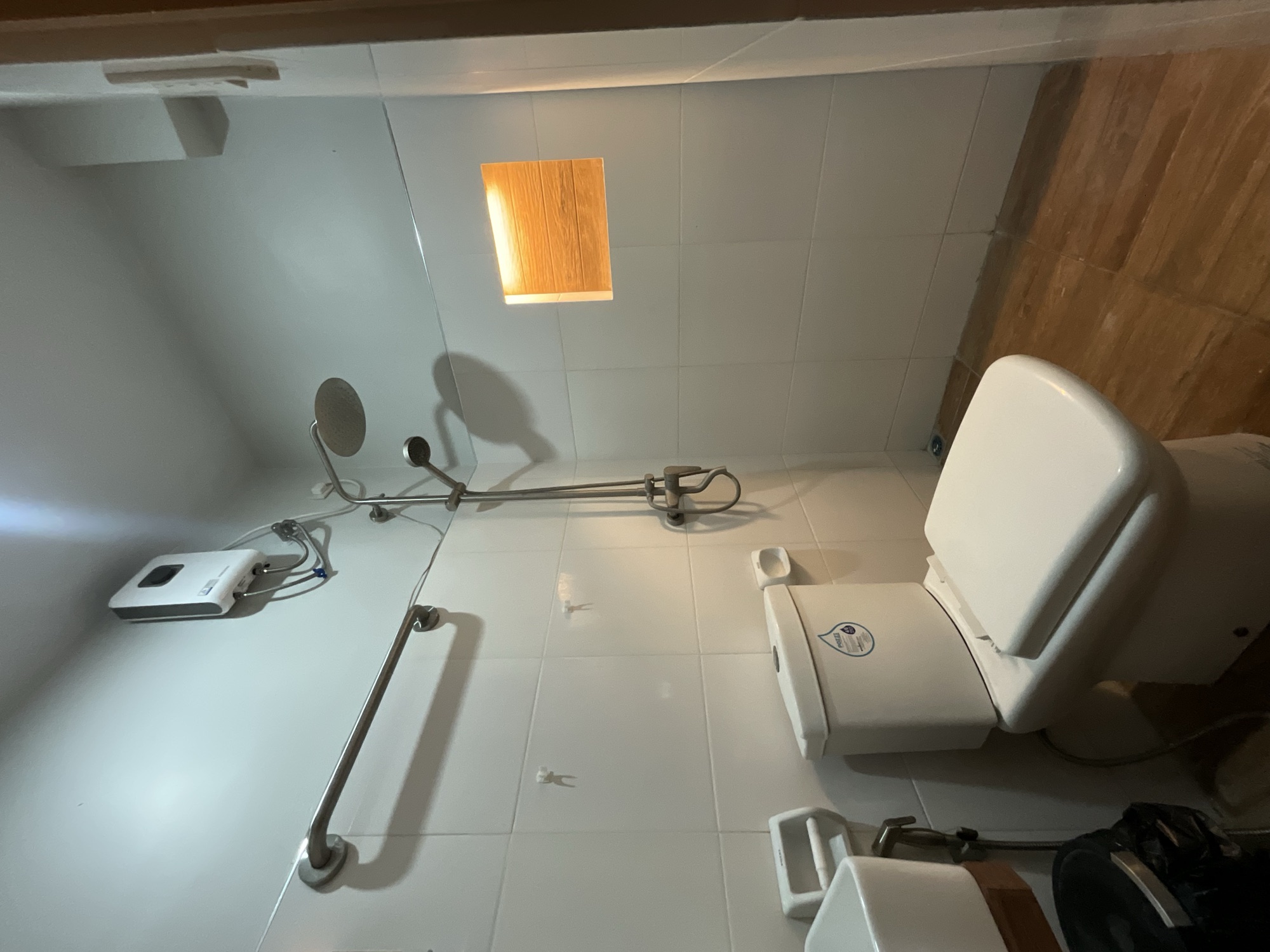 Tiled bathroom with a rain shower on a riser, toilet and basin