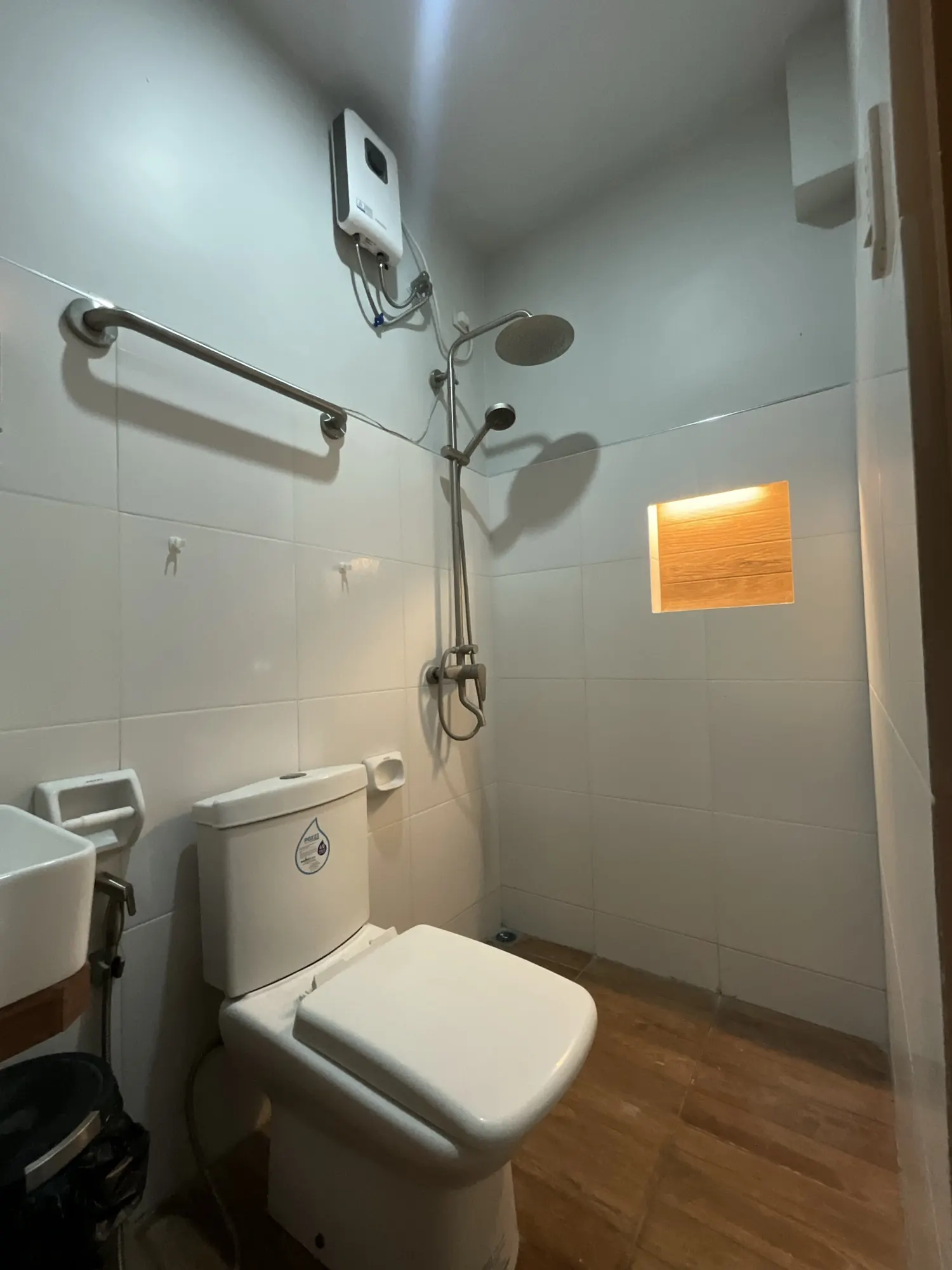 Tiled bathroom with a rain shower on a riser, toilet and basin