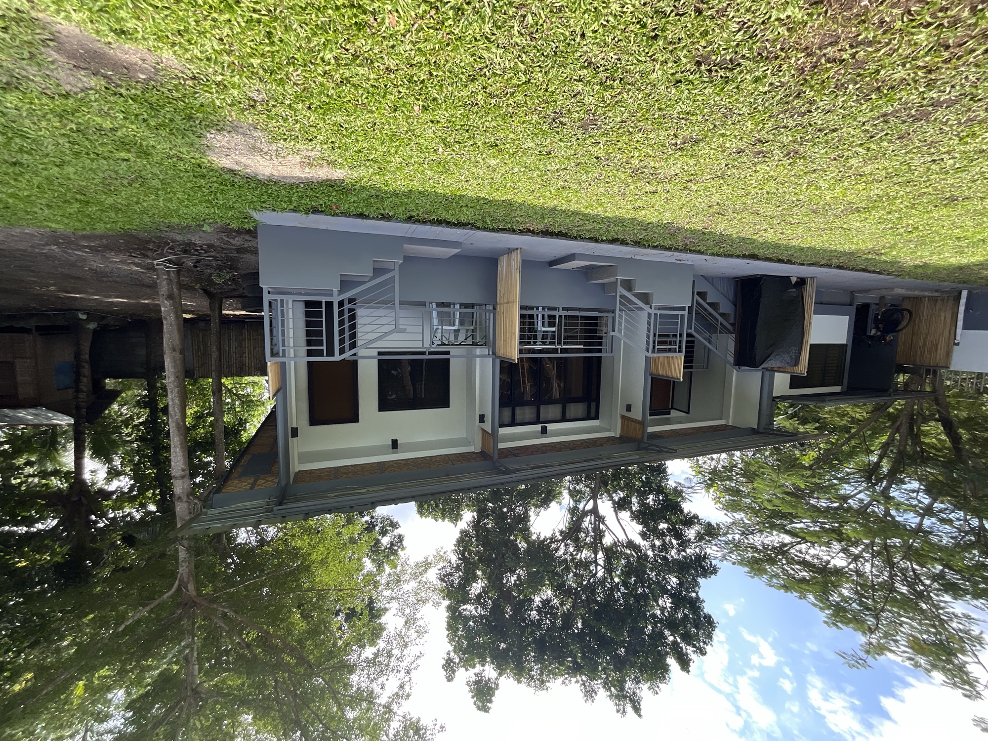A row of rental rooms at PaPio's Nest with porches facing a green lawn and tall trees