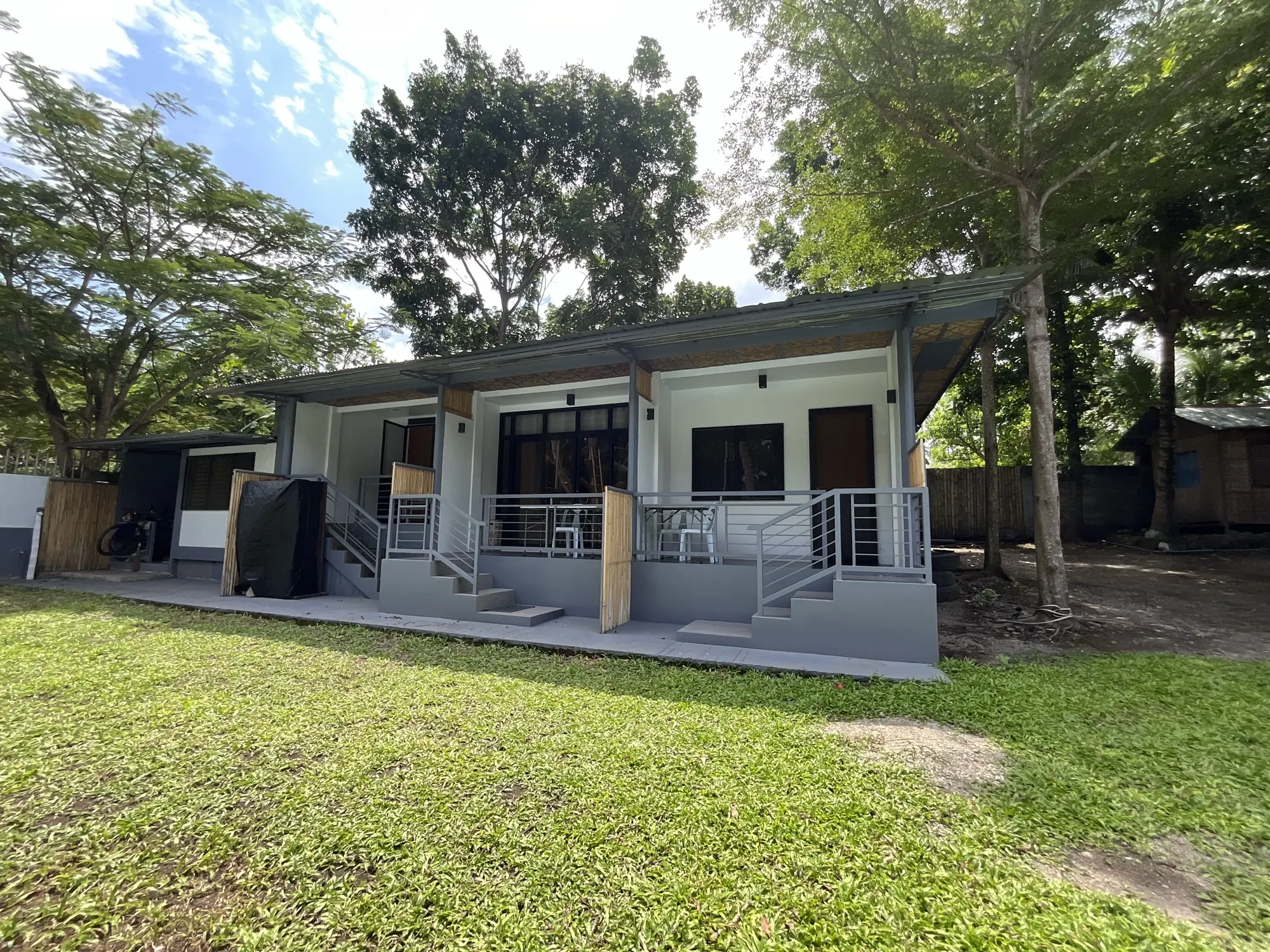 A row of rental rooms at PaPio's Nest with porches facing a green lawn and tall trees