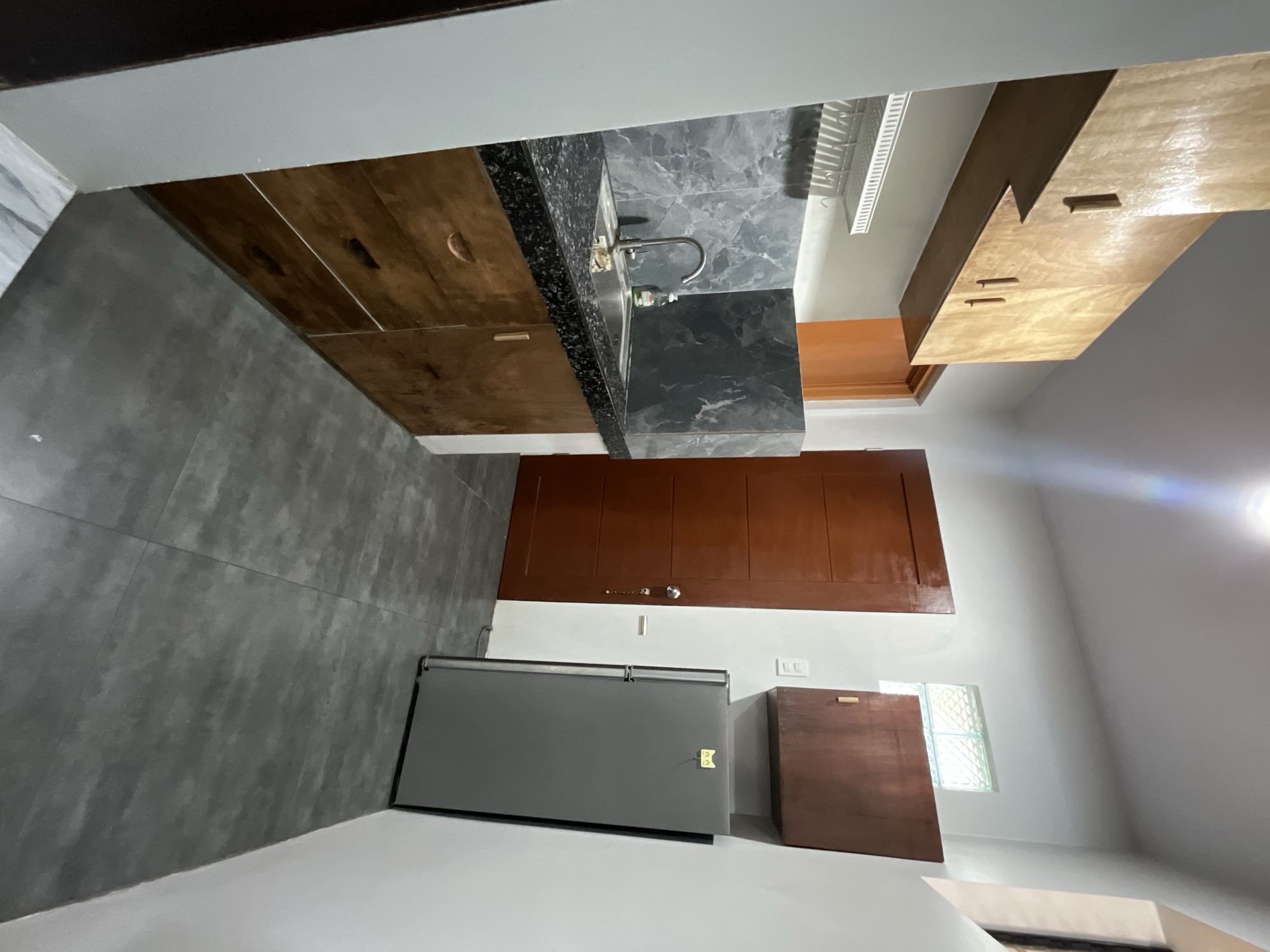 Kitchenette with stone counter, sink, cupboards and a full-height fridge