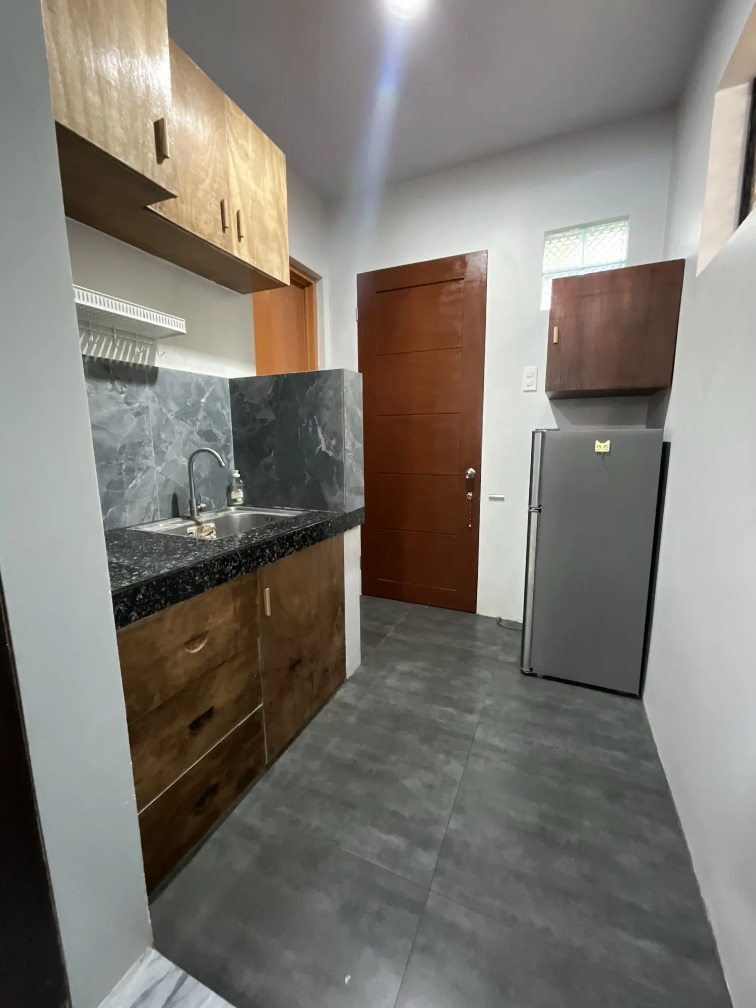 Kitchenette with stone counter, sink, cupboards and a full-height fridge