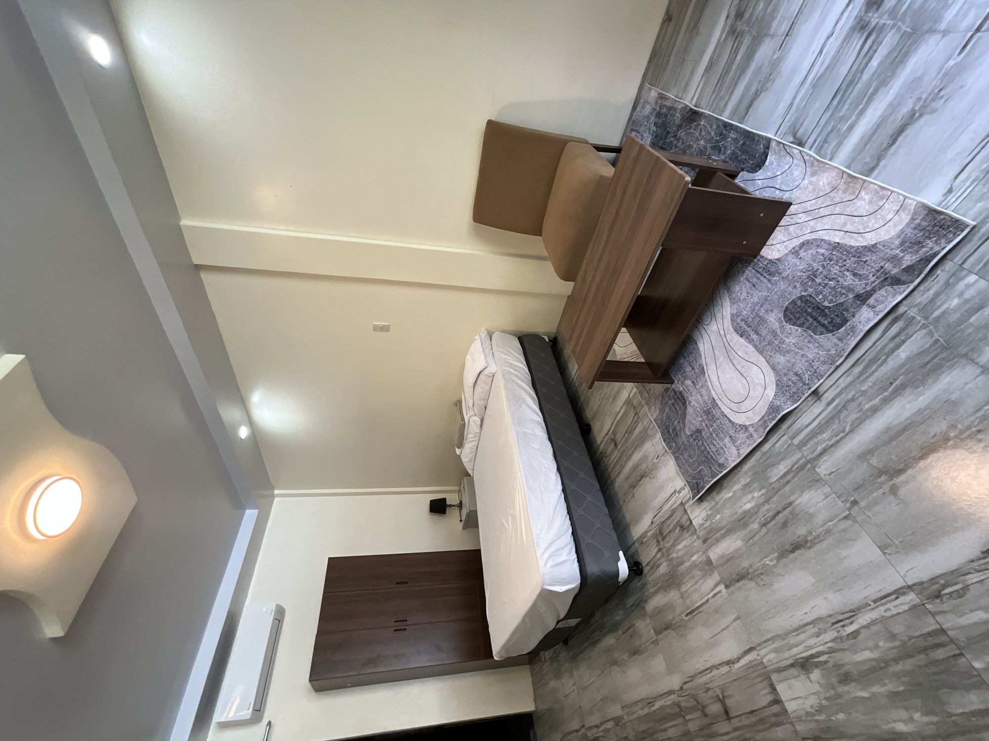 Room with a single bed, an armchair and a wooden bench