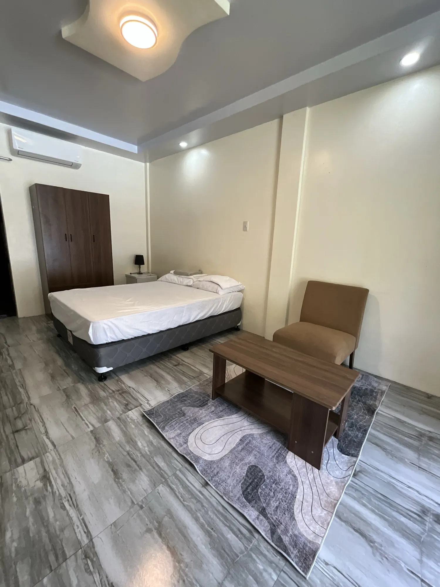 Room with a single bed, an armchair and a wooden bench