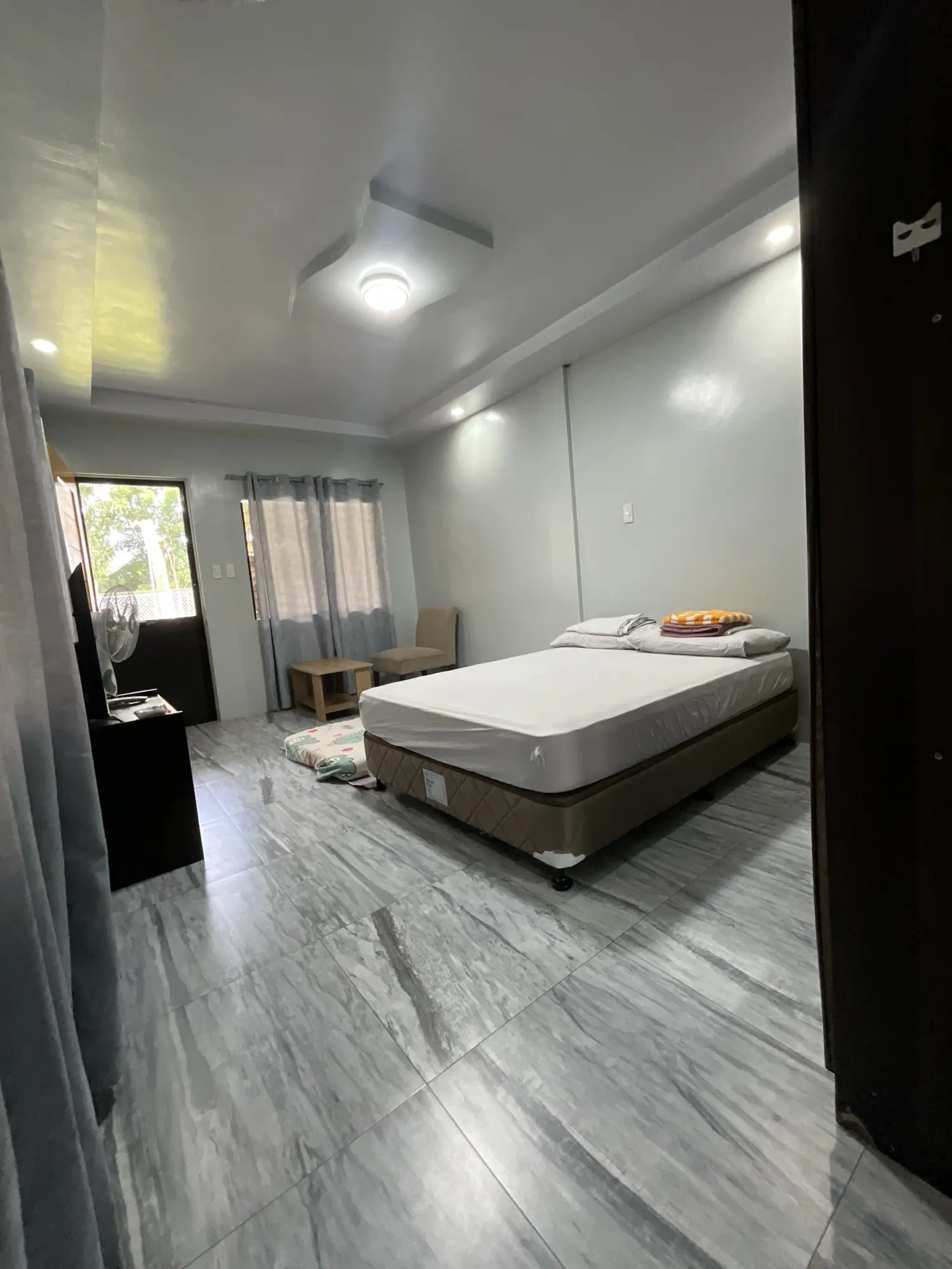 Room with a bed beside a curtained window