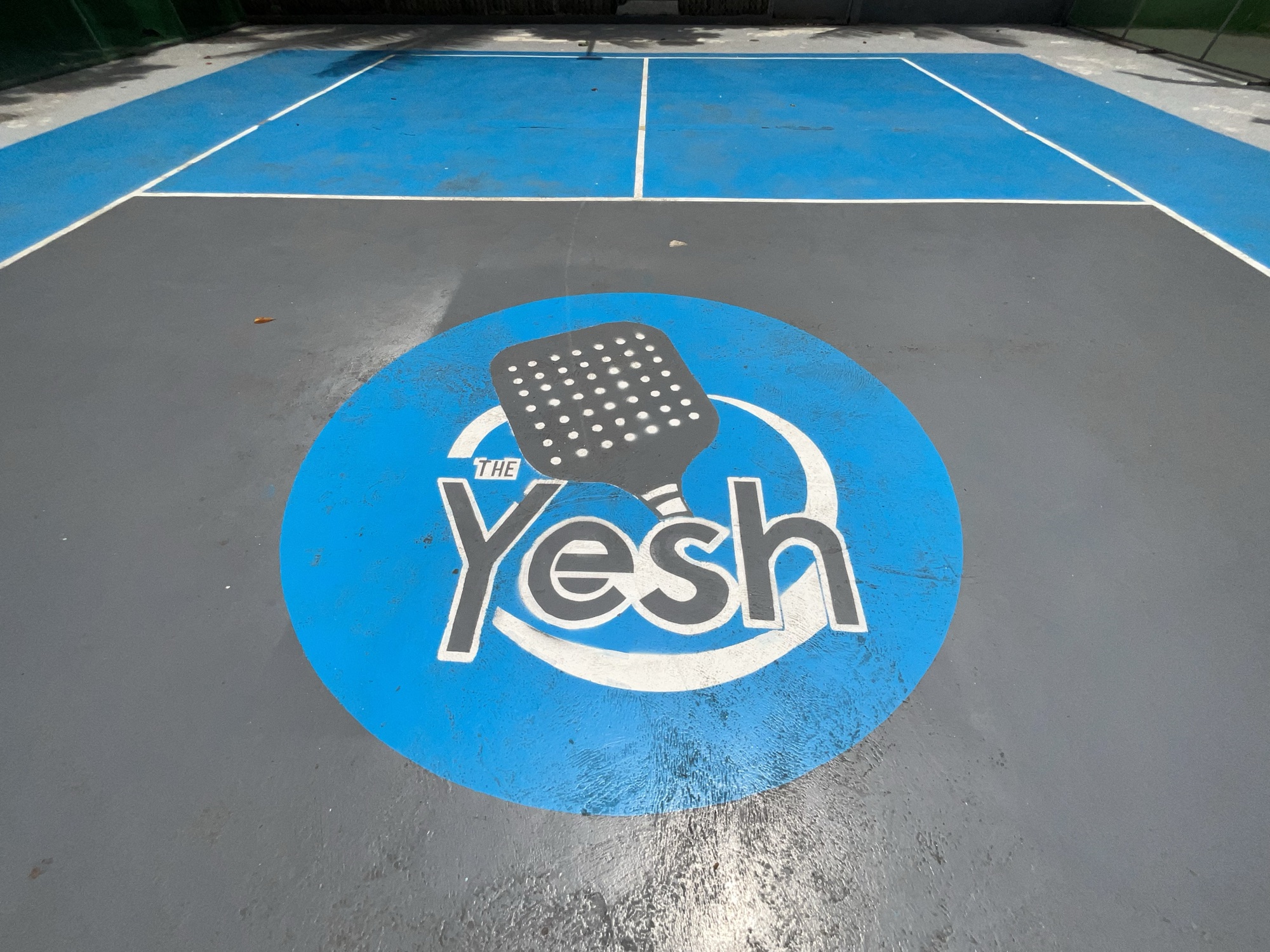 The Yesh logo painted in a circle on the court surface